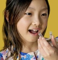 Young girl holding a clear orthodontic aligner